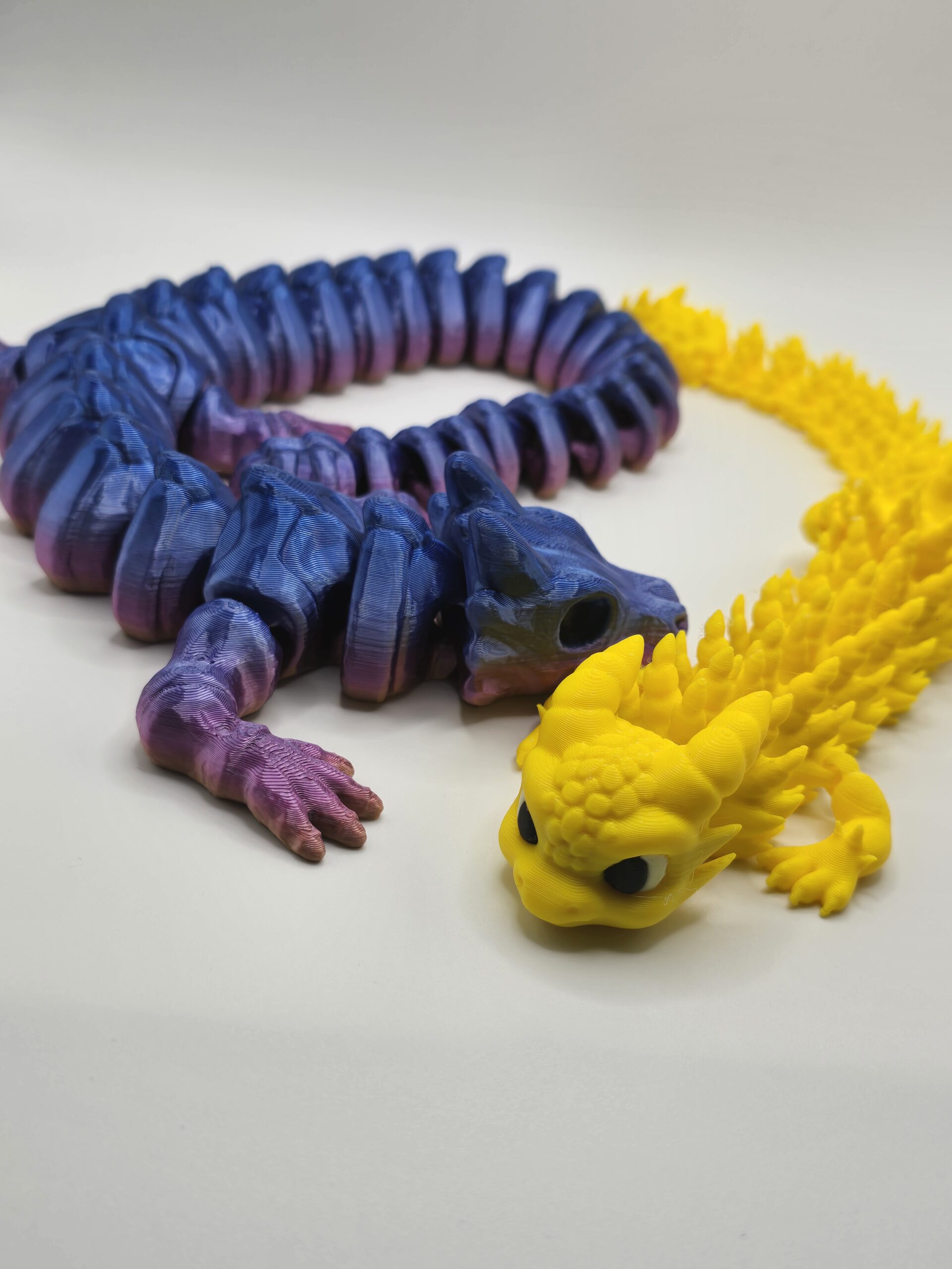 Picture shows two 3D printed dragons, in multi blue/purple and yellow colors
