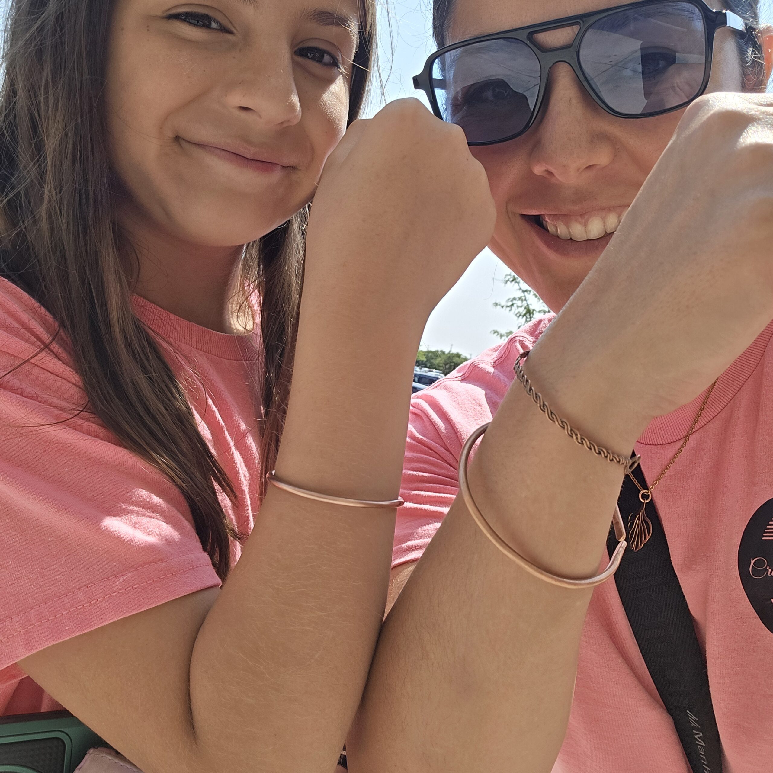 A joyful photo of two people wearing handmade copper bangles, showing their warm metallic glow in natural sunlight. The minimalist design complements casual outfits and highlights the timeless appeal of handcrafted copper jewelry.