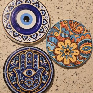 A set of three UV‑printed porcelain coasters showcasing boho floral, Hamsa hand, and evil eye designs. Each piece combines vivid color, cultural artistry, and durable craftsmanship for stylish tabletop protection.